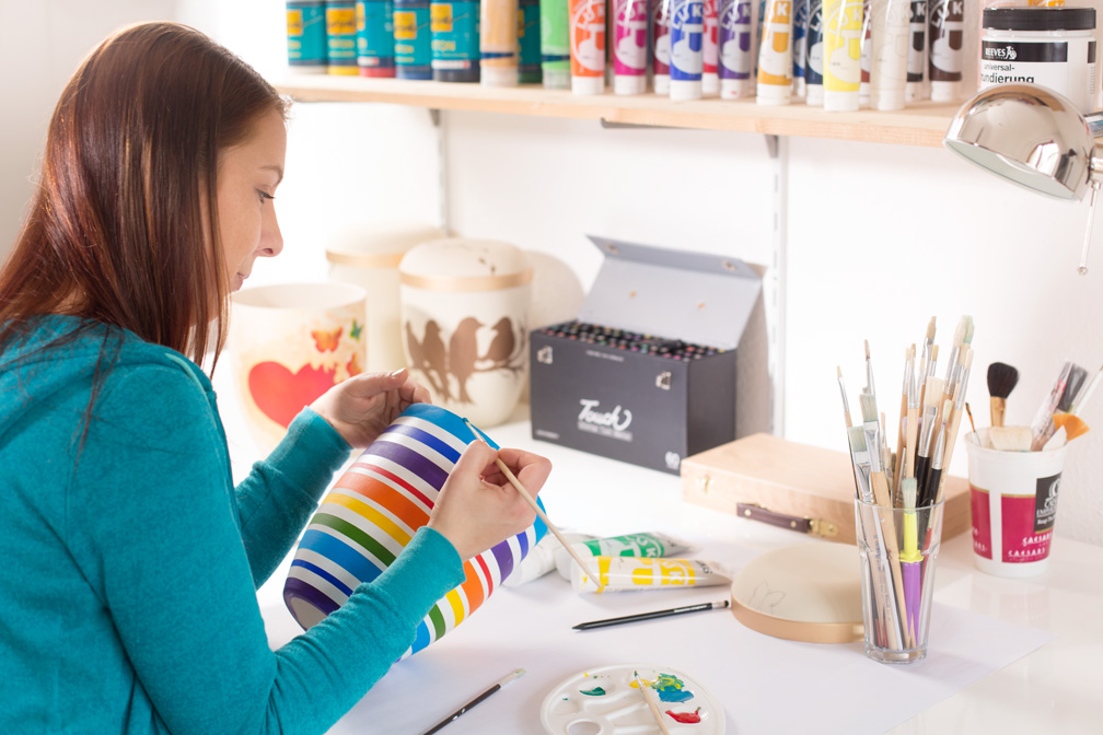 Julia bei der Bemalung einer Natururne aus biologischem Material. Es entsteht die Urne"Stripes"